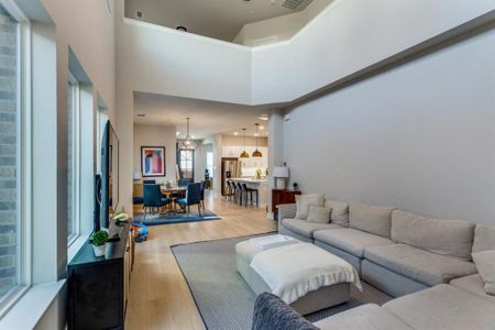 Living area with a towering ceiling, light wood finished floors, and visible vents