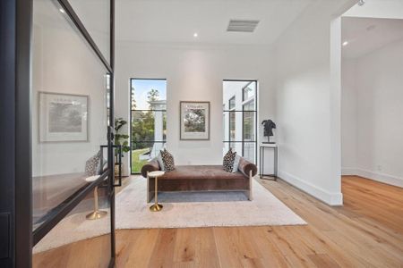 This grand entryway, framed by sleek steel windows and a striking front door, offers a stunning view of the expansive back lawn. The wide, open space provides the perfect setting to showcase impressive artwork, making a bold first impression. To the left, you'll find the first-floor study, creating a seamless blend of elegance and functionality.