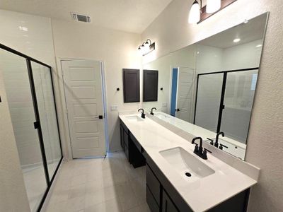 Primary bathroom with dual vanities and walk-in shower