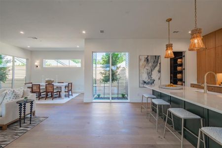 Kitchen featuring light hardwood / wood-style floors, decorative light fixtures, sink, and a breakfast bar area