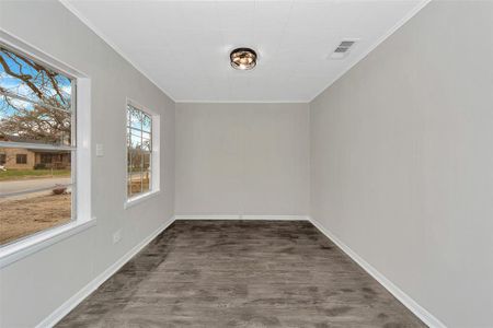 Empty room featuring baseboards, visible vents, dark wood finished floors, and ornamental molding