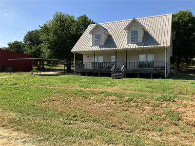 View of house with covered porch and a lawn