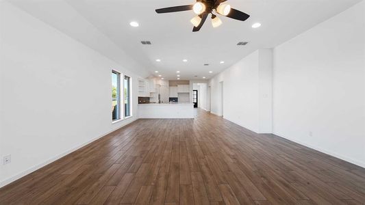 Unfurnished living room featuring ceiling fan and dark wood-type flooring