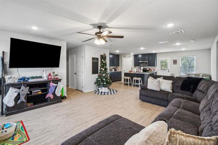 Living room with ceiling fan and light hardwood / wood-style flooring