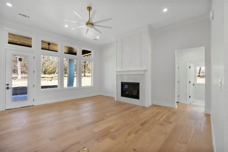 Unfurnished living room featuring crown molding, light hardwood / wood-style flooring, and ceiling fan