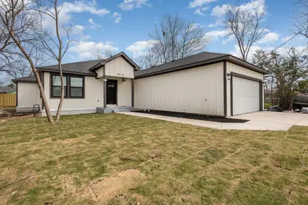 View of front of property featuring a front yard, a garage, driveway, and roof with shingles