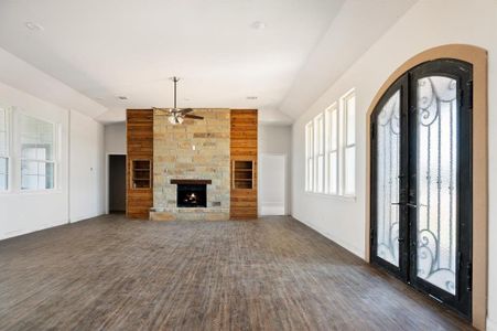 Unfurnished living room with ceiling fan, a fireplace, french doors, and dark wood-type flooring