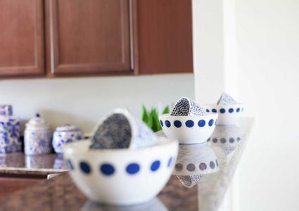 Driftwood model home kitchen stage with blue china dishes including cookie jars, food storage containers, and white bowls with blue dots and cups sitting inside