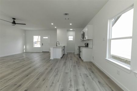 Unfurnished living room with ceiling fan, a wealth of natural light, sink, and light hardwood / wood-style flooring