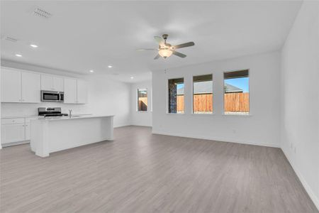 Kitchen featuring ceiling fan, a kitchen island with sink, white cabinetry, stainless steel appliances, and light hardwood / wood-style floors