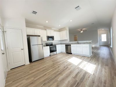 Kitchen includes granite countertops, luxury vinyl plank flooring, 36” upper cabinets with crown molding, a full suite of stainless-steel Whirlpool appliances – including refrigerator with ice maker, recessed lighting, and a large single basin sink.