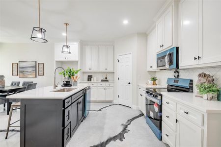 Kitchen featuring white cabinetry, stainless steel appliances, tasteful backsplash, and sink