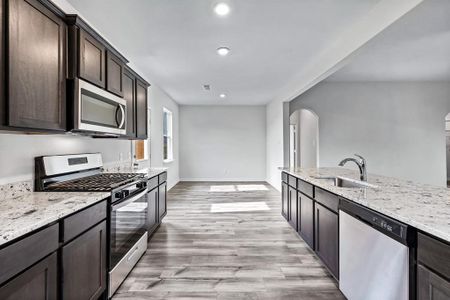 Kitchen with sink, light hardwood / wood-style flooring, light stone countertops, and stainless steel appliances