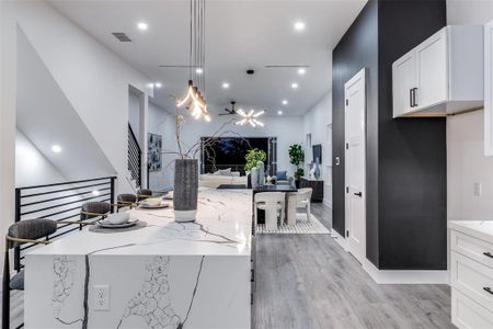 Kitchen featuring light hardwood / wood-style floors, a notable chandelier, light stone counters, and white cabinets