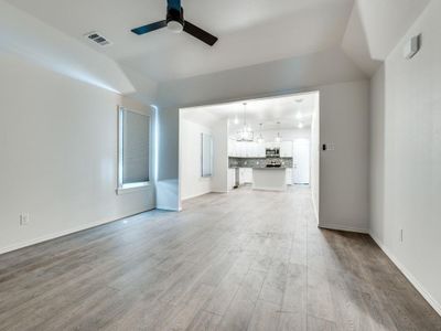 Unfurnished living room with ceiling fan, vaulted ceiling, and light hardwood / wood-style flooring