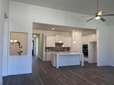 Kitchen featuring dark wood-style floors, white cabinets, oven, and backsplash