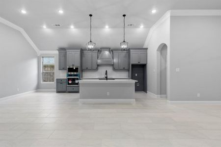 Kitchen featuring gray cabinets, lofted ceiling, crown molding, and appliances with stainless steel finishes