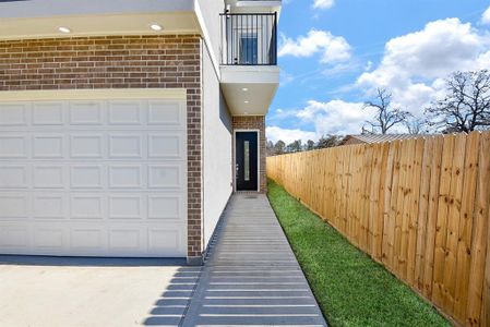 This modern entryway features a sleek walkway leading to a stylish glass-panel front door. The combination of brick and contemporary design elements creates a warm yet sophisticated curb appeal.