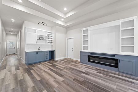 Unfurnished living room with wet bar, built in features, and hardwood / wood-style floors