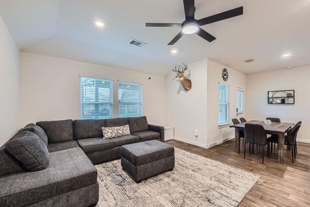 Living room featuring visible vents, ceiling fan, wood finished floors, and baseboards Living room featuring visible vents, ceiling fan, wood finished floors, and baseboards