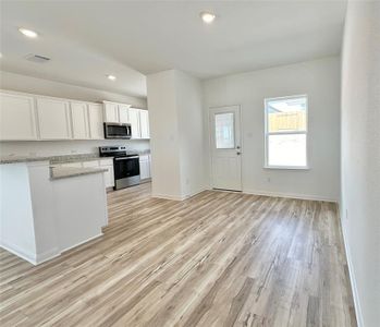 Kitchen includes granite countertops, luxury vinyl plank flooring, 36” upper cabinets with crown molding, a full suite of stainless-steel Whirlpool appliances – including refrigerator with ice maker, recessed lighting, and a large single basin sink.