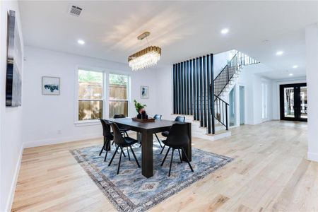 Dining area with french doors, a chandelier, and light wood-type flooring