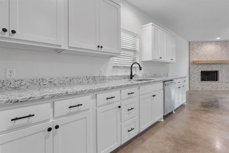 Kitchen with dishwasher, sink, a large fireplace, and white cabinets