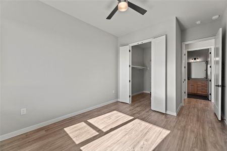 Unfurnished bedroom featuring ceiling fan, a walk in closet, a closet, and light hardwood / wood-style flooring