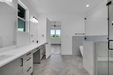 Bathroom featuring ceiling fan, double sink vanity, parquet floors, and independent shower and bath