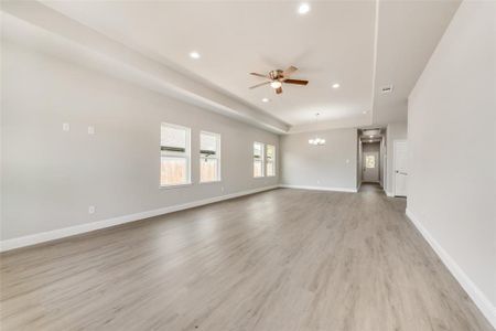 Unfurnished living room with ceiling fan with notable chandelier and light wood-type flooring