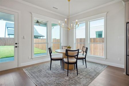 Dining space with a chandelier, ornamental molding, hardwood / wood-style flooring, and a wealth of natural light