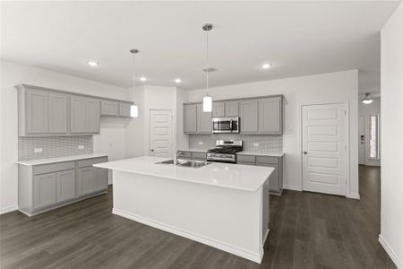 Kitchen featuring hanging light fixtures, an island with sink, stainless steel appliances, and dark hardwood / wood-style floors