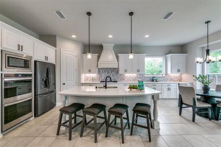 Kitchen with white cabinetry, backsplash, custom range hood, and stainless steel appliances