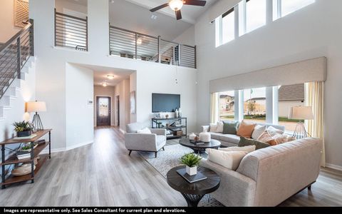 Living area with a towering ceiling, baseboards, a ceiling fan, and wood finished floors Living area with a towering ceiling, baseboards, a ceiling fan, and wood finished floors