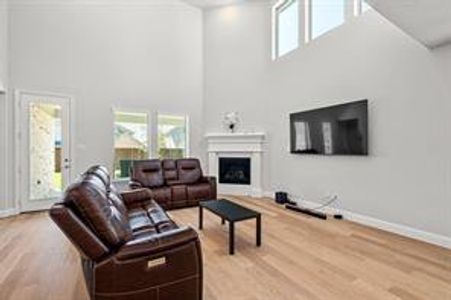 Living room with light wood-type flooring and a towering ceiling