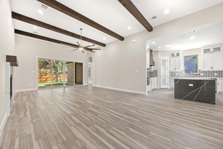 Unfurnished living room featuring ceiling fan, beamed ceiling, sink, and light hardwood / wood-style floors