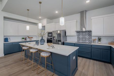 Kitchen featuring a kitchen island, blue cabinets, black appliances, light hardwood / wood-style flooring, and wall chimney range hood