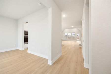 Hallway featuring lofted ceiling and light wood-type flooring