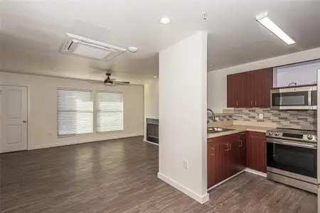 Kitchen with stainless sink, decorative backsplash, ceiling fan, luxury vinyl wood-style floors, and stainless steel appliances