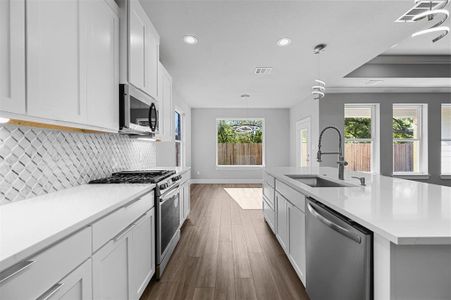 Kitchen with white cabinets, SS appliances and gas range