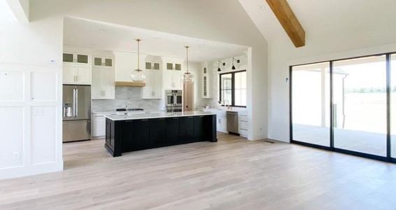 Kitchen with appliances with stainless steel finishes, hanging light fixtures, white cabinetry, a kitchen island, and beamed ceiling