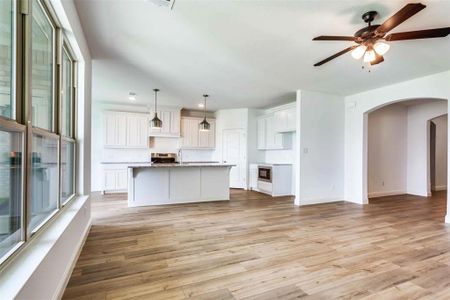 Kitchen featuring light wood-type flooring, a center island with sink, pendant lighting, and ceiling fan