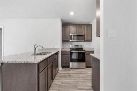 Kitchen featuring light hardwood / wood-style floors, dark brown cabinets, sink, stainless steel appliances, and kitchen peninsula