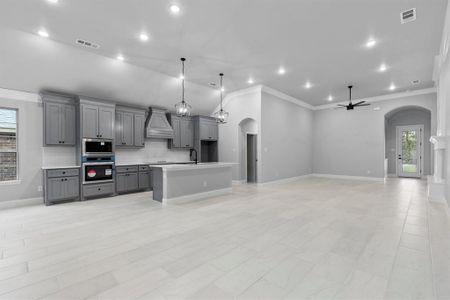 Kitchen featuring gray cabinetry, ceiling fan, stainless steel appliances, decorative light fixtures, and custom exhaust hood