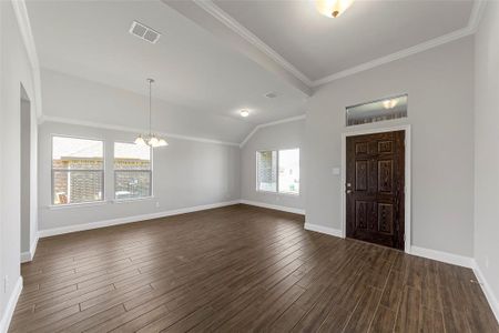 Entryway with dark hardwood / wood-style flooring, an inviting chandelier, vaulted ceiling, and crown molding