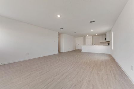 Unfurnished living room featuring baseboards, light wood-style flooring, visible vents, and recessed lighting