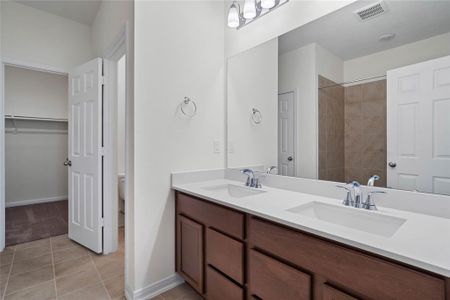 This primary bathroom is definitely move-in ready! Featuring an oversized tub/shower combo with tile surround, stained cabinets with light countertops, large walk-in closet, high ceilings, neutral paint, sleek and modern finishes.