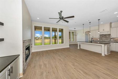 Unfurnished living room with sink, ceiling fan, a brick fireplace, and light hardwood / wood-style flooring