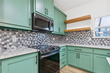 Kitchen with appliances with stainless steel finishes, tasteful backsplash, and green cabinetry