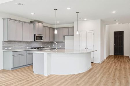 Kitchen with backsplash, light wood-type flooring, gray cabinetry, and stainless steel appliances